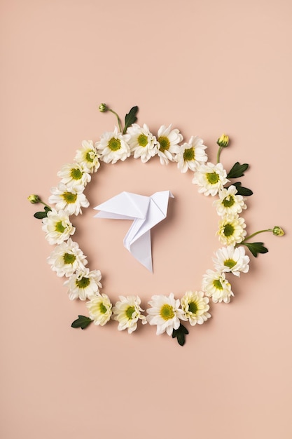Premium Photo | Origami dove in a flower wreath on a gentle backgrou