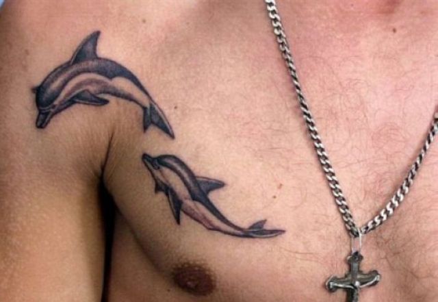 Two dolphin tattoos on the chest and shoulder | Dolphins tattoo .